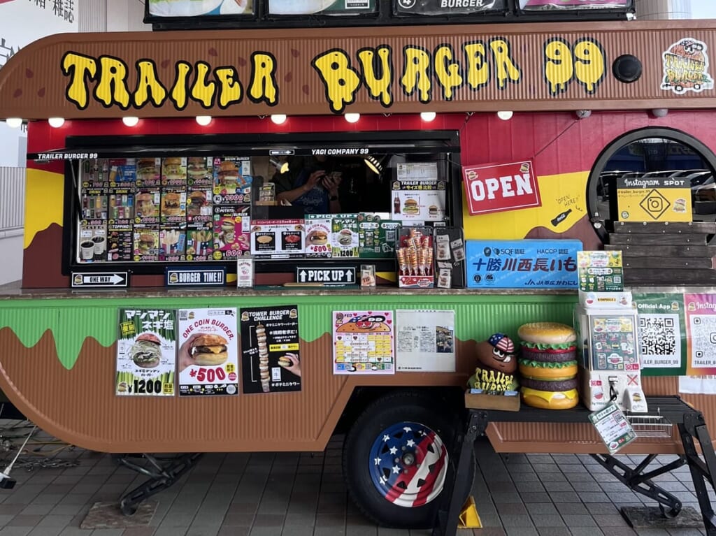 TRAILER BURGER 99　トレーラーバーガー99　キッチンカー　大型キッチントレーラー　移動販売　開業1周年　オープン以来、新鮮　十勝産食材　十勝産　北海道産　安心　安全　長いも　グルーンアスパラ　野菜類　マッシュルーム　チーズ　牛肉　北海道産小麦 100%バンズ　クラフトバーガー　提案　限定商品　人気　ハンバーガー　帯広市　十勝管内　新得町　幕別町　プレゼント　特典　TRAILER BURGER 99　トレーラーバーガー99　キッチンカー　大型キッチントレーラー　移動販売　開業1周年　オープン以来、新鮮　十勝産食材　十勝産　北海道産　安心　安全　長いも　グルーンアスパラ　野菜類　マッシュルーム　チーズ　牛肉　北海道産小麦 100%バンズ　クラフトバーガー　提案　限定商品　人気　ハンバーガー　帯広市　十勝管内　新得町　幕別町　マグプラネット　2024年6月　メムロピーナッツ　メムピー　メムピーナッツバターメープルクリームチーズベーコンバーガー　新顔作物　落花生　にんにく　さつまいもをPRする企画　とかちの農業推し勝プロジェクト　十勝ハーブ牛　イトーヨーカドー帯広　トレバガベース　新規オープン　オープン　グランドオープン　開店　新規開店　OPEN　2024年9月9日（月）11時　〒089-0538 北海道中川郡幕別町札内共栄町１６−４　インデアン 札内店　みずほ通り歯科クリニック　美味館　メニュー　場所　イートイン　テイクアウト　駐車場　国道38号線　北海道　幕別町　札内