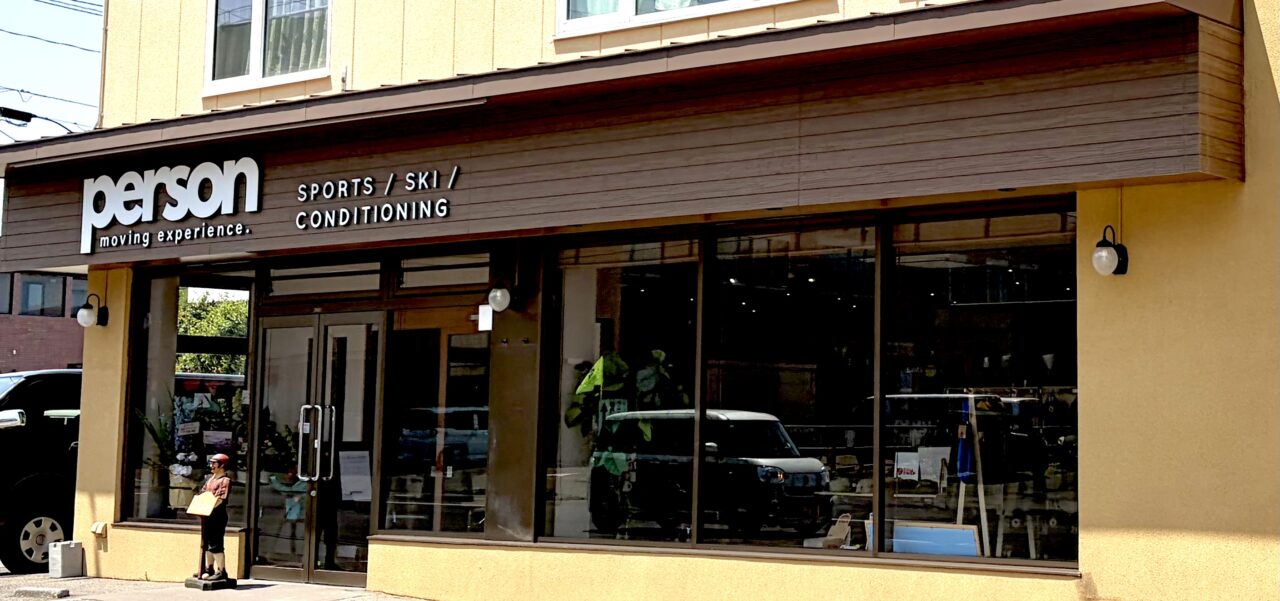 スポーツ専門店PERSON新店舗外観 北海道帯広市東4条南11丁目19番地3 郵便番号080-0804 2026年6月20日土曜日移転リニューアルオープン 元クックチャム帯広店跡地の建物 平屋建て 店舗入口の正面ガラス扉 自動ドア 青い看板 白い文字でPERSON スポーツショップ 十勝のスポーツパートナー ダイイチ東店のすぐ北側 道路沿いの店舗 営業中 駐車場あり NTTの大きな鉄塔から東へ進んだ場所 斉川漢方薬局の隣 帯広駅から車でアクセスしやすい立地 明るい昼間の写真 店舗正面の景色