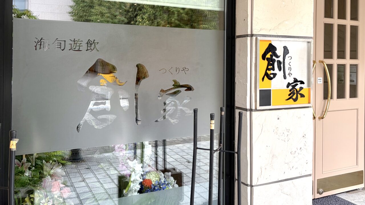 18年間にわたり北の屋台を牽引した名店が卒業し、令和8年(2026年)8月20日(木曜日)に待望の独立グランドオープンを果たした、〒080-0011 北海道帯広市西1条南9丁目3-6の東銀座通り沿いに佇む創作和食店「創家(つくりや)」の真新しい路面店舗の外観全体。地元を代表する銘菓・六花亭帯広本店の駐車場の真向かいという一等地に位置し、新品の香りが漂うような美しく均整の取れた木目の外壁と、モダンで洗練された引き戸のエントランスが美しい平屋風のデザイン。十勝・帯広の新しい美食スポットの誕生を告げる、新しく綺麗な建物が東銀座通りの街並みに調和している様子を捉えた写真。令和8年(2026年)8月20日の新店舗始動に合わせて完全リニューアルされた、〒080-0011 北海道帯広市西1条南9丁目の創作和食店「創家(つくりや)」のファサード(店舗正面)を飾る新しい店舗看板のクローズアップ。これまでの屋台時代の親しみやすさを継承しながらも、より大人の隠れ家としての品格を感じさせるスタイリッシュで美しいフォントで「創家」の文字が立体的に刻まれているデザイン。帯広の夜の繁華街・東銀座通りに集う人々を温かく迎え入れるように、内部からの優しいバックライトが店名を美しく浮かび上がらせており、新時代の幕開けを象徴する、夜の街の新たなランドマークとしての存在感を放っている様子。
