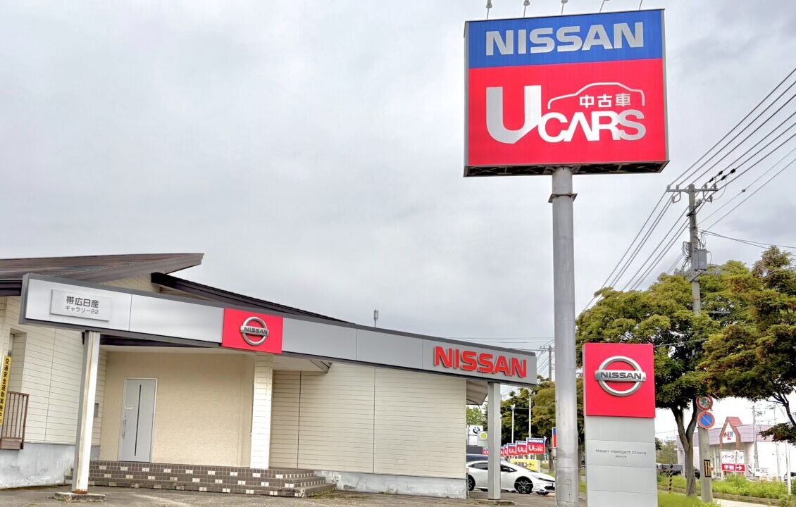 六花亭ガーデンの斜向かい　白樺通り沿いに店舗構えている帯広日産自動車株式会社 ギャラリー２２店の看板　赤で中古車　青でNISSANの文字が目立つ看板　ギャラリー２２の外観もわかりやすい　白い壁と大きな駐車場が特徴　帯広日産 ギャラリー２２、〒080-2472 北海道帯広市西２２条南３丁目21番地　2026年9月20日（日）閉店　最終営業日9月20日（日）　帯広日産自動車株式会社　ドーム店は2026年ン8月31日（月）閉店　最終営業日　8月31日（月）　〒080-0017 北海道帯広市西７条南２０丁目 1番地　中古車専門店が新規オープン　帯広日産 中古車ドーム店、〒080-0017 北海道帯広市西７条南２０丁目 1番地　イオン帯広店の直ぐそば