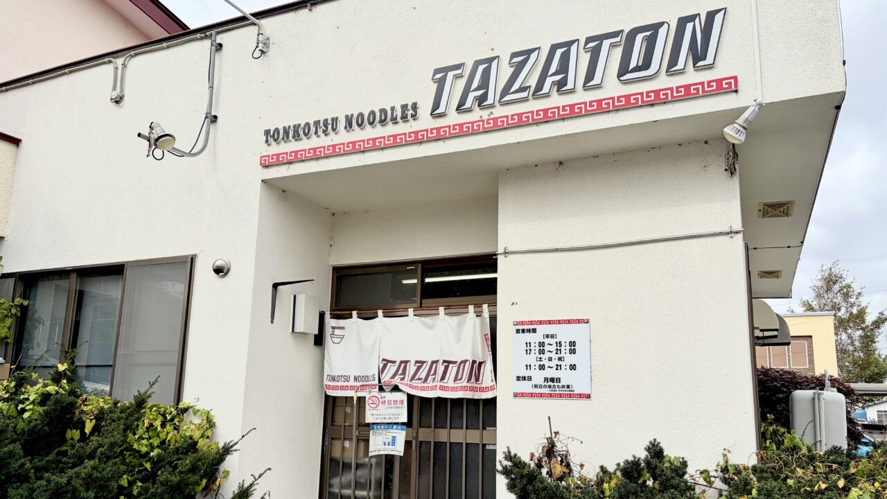 トンコツ ヌードルズ TAZATON 帯広のラーメン店 豚骨ラーメンが人気 住所は〒080-0050 北海道帯広市白樺16条東7丁目6−6 敷地内に駐車場もあるので車でも安心 写真は店舗外観で白い建物 看板にはTONKOTSU NOODLES TAZATONと記載されている